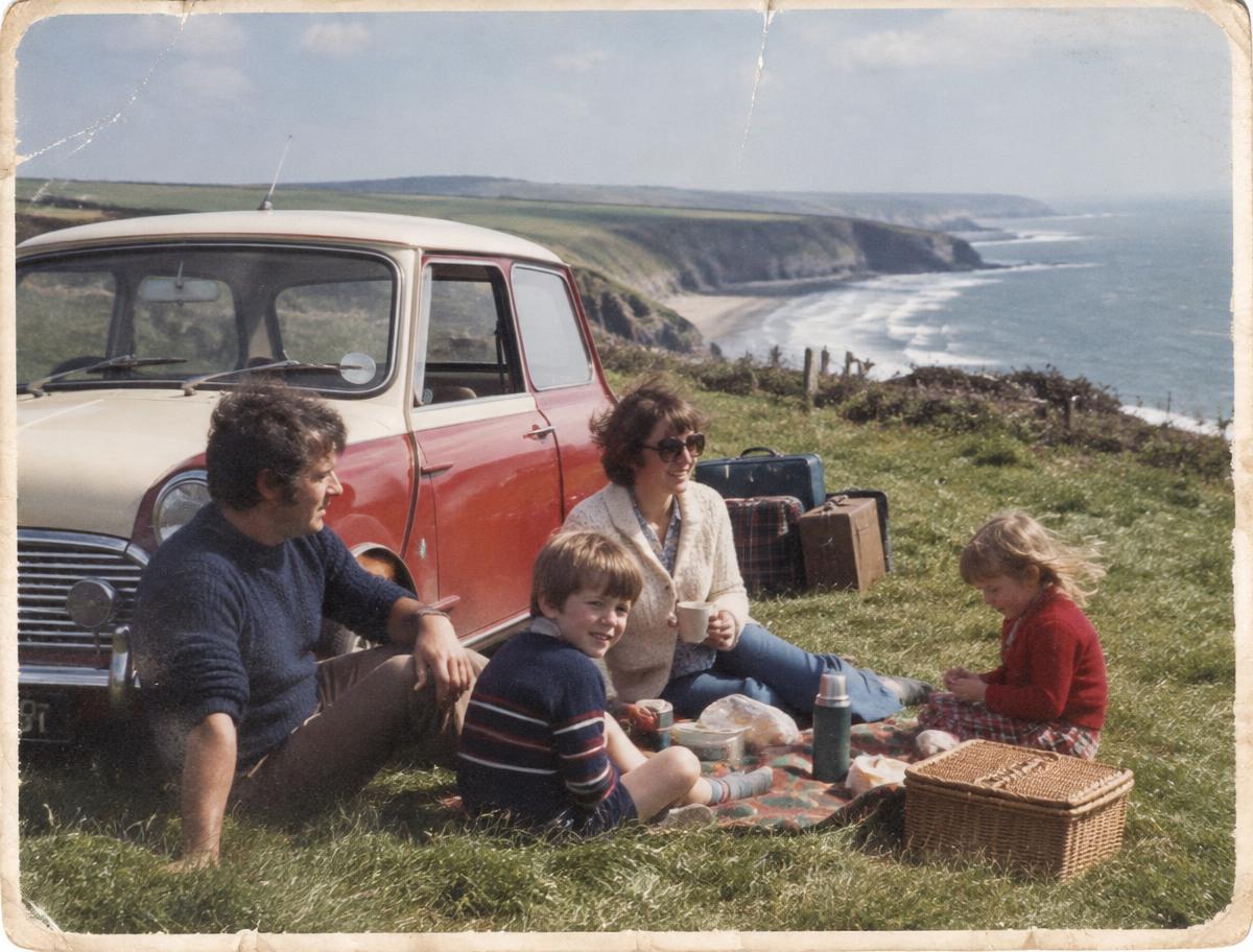 A family picnic beside a Mini on a 1970s coastal holiday